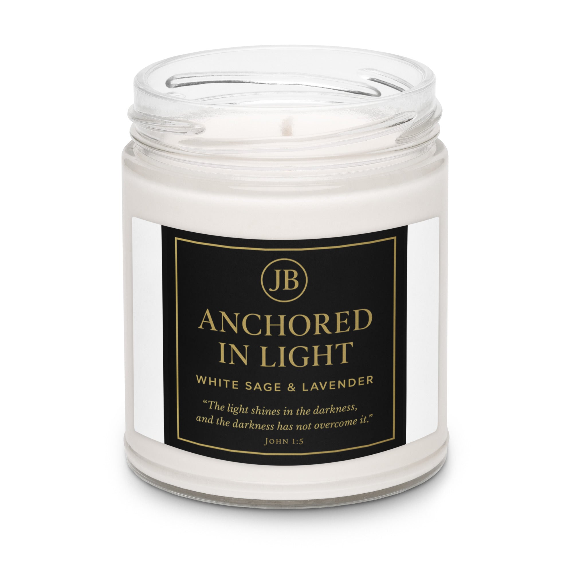 “‘Anchored in Light’ candle in a clear glass jar without a lid, showcasing white wax and a black and gold JB label. The label features the White Sage & Lavender scent and John 1:5 scripture: ‘The light shines in the darkness, and the darkness has not overcome it.’ Minimal luxury product display on a white background.”