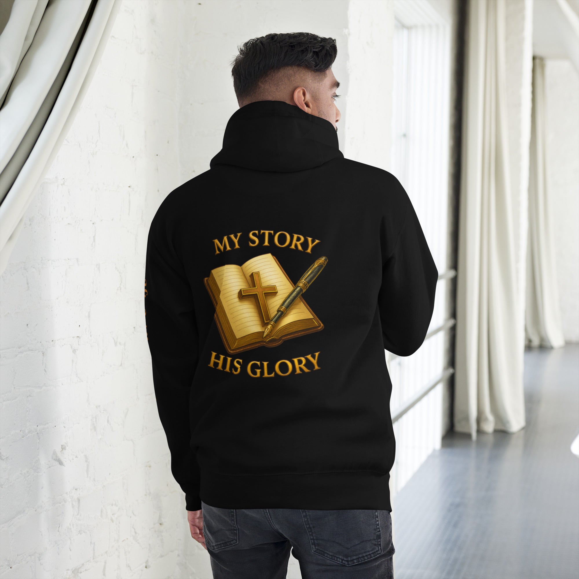 “Back view of black hoodie with gold Bible, cross, and pen graphic, featuring the words My Story His Glory.”